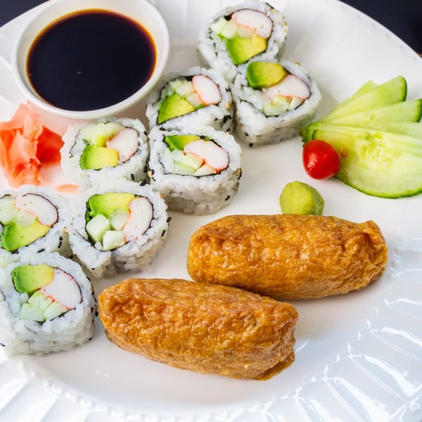 MAJÉ Sushi California rolls and inari sushi with soy sauce, ginger, wasabi, and cucumber.