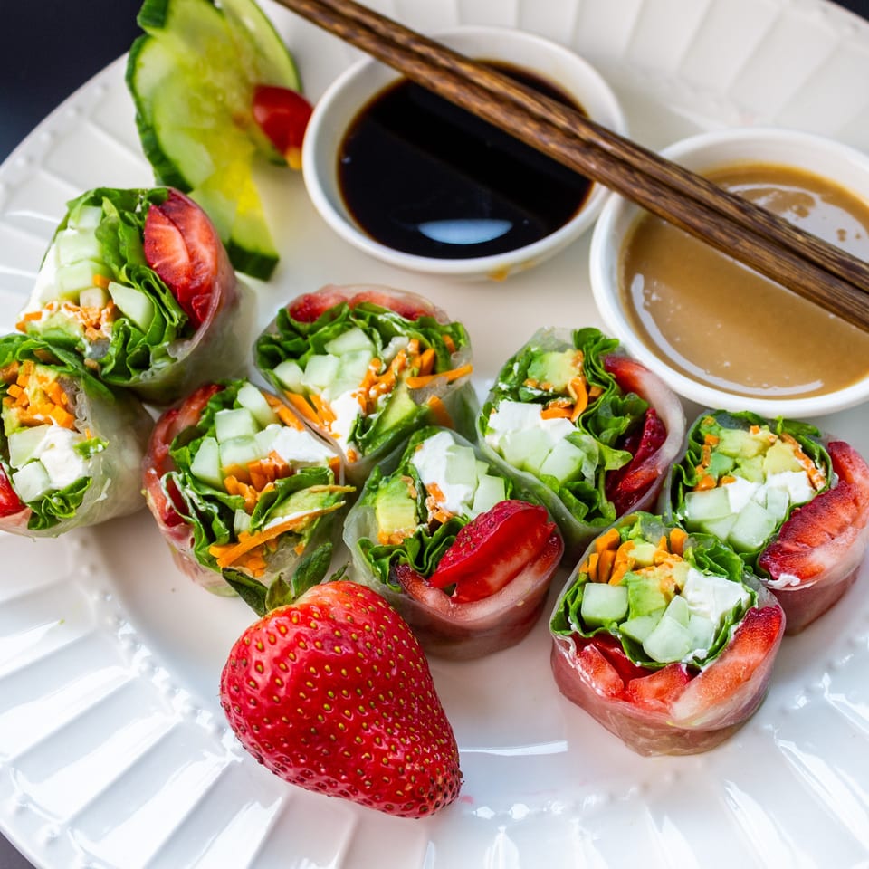Fresh spring rolls with strawberries, lettuce, cucumber, and carrots, served with soy and peanut sauces.