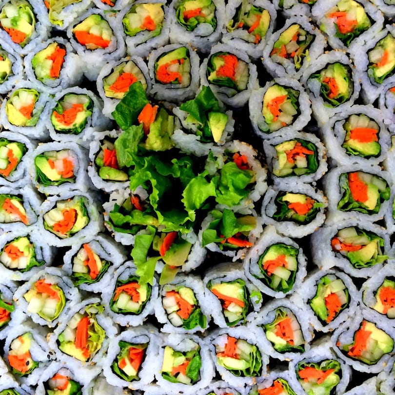 Overhead view of MAJÉ Sushi's vegetable rolls with avocado, carrots, and lettuce, arranged in a grid.