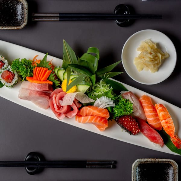 Overhead view of a MAJÉ Sushi platter with various sashimi, nigiri, and a tuna roll.